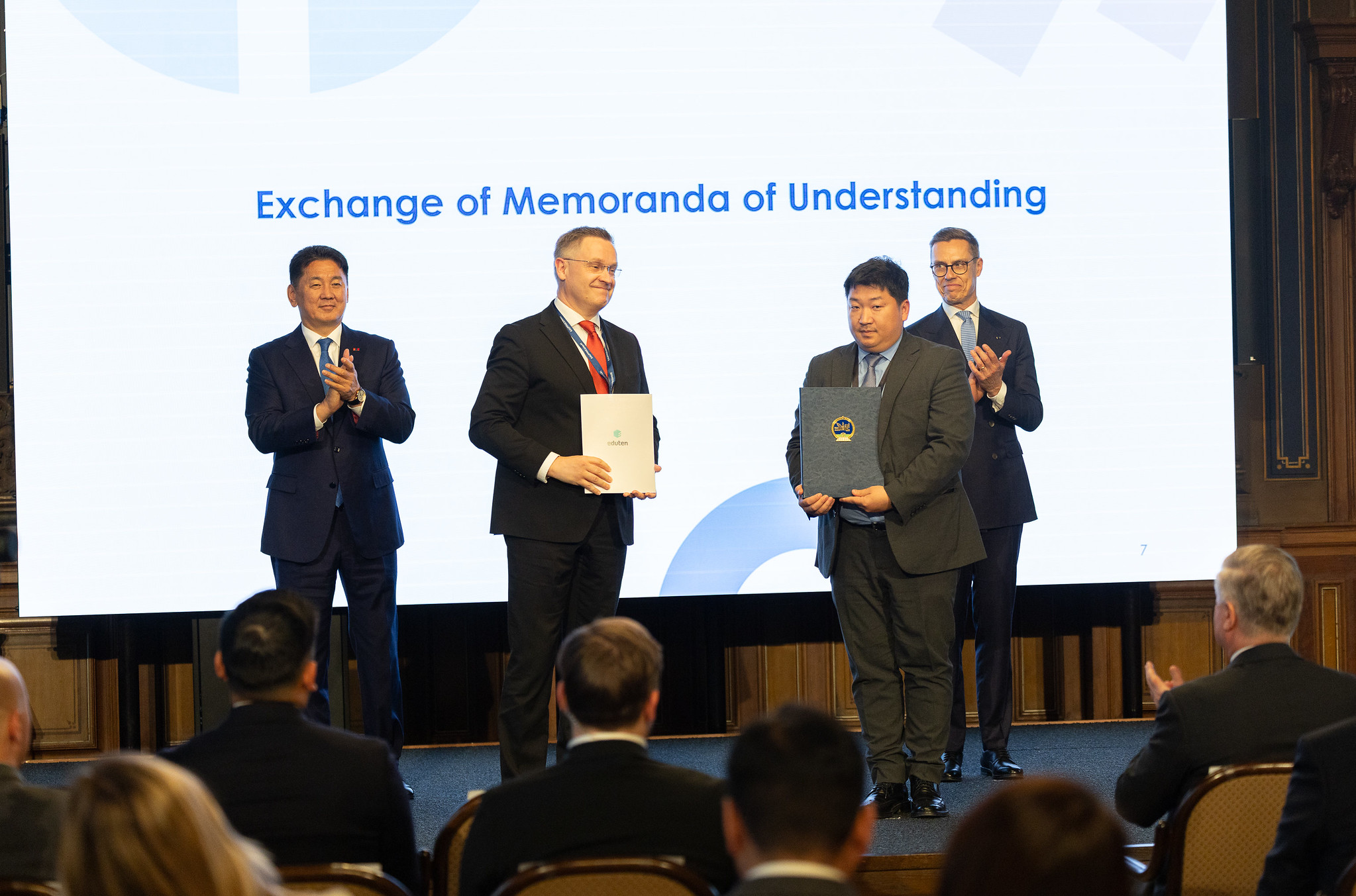 Henri Muurimaa of Eduten and Enkhbayar Baatartsol of the Ministry of Education of Mongolia holding the signed MoU, with the Presidents of Mongolia and Finland applauding